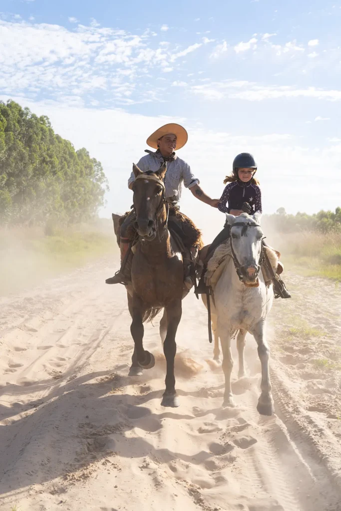 A guacho helping a young girl to learn criollo horse riding