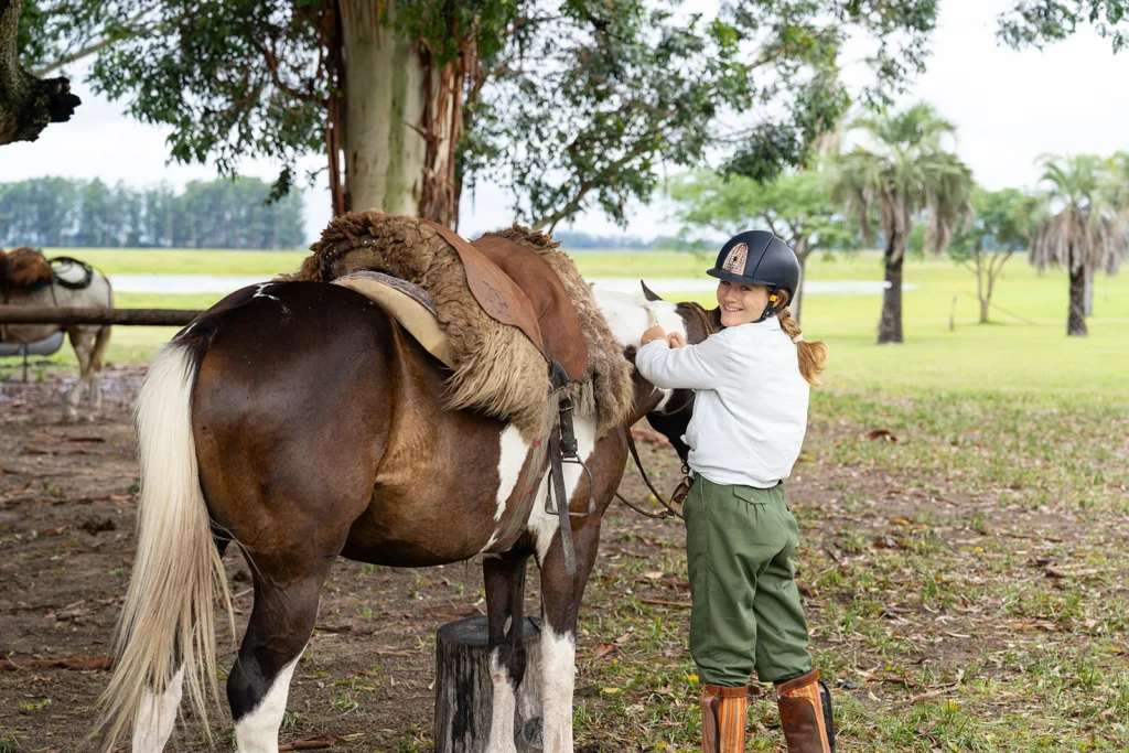 A girl with a horse dressed in green gaucho bombachas