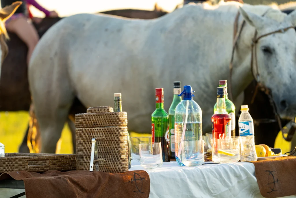 A table of drinks outside with horses behind them